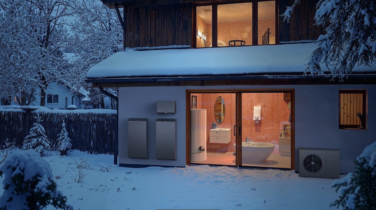 Eine Wärmepumpe, ein Batteriespeicher und ein Durchlauferhitzer, die ein Haus im Winter mit Wärme und Energie versorgen