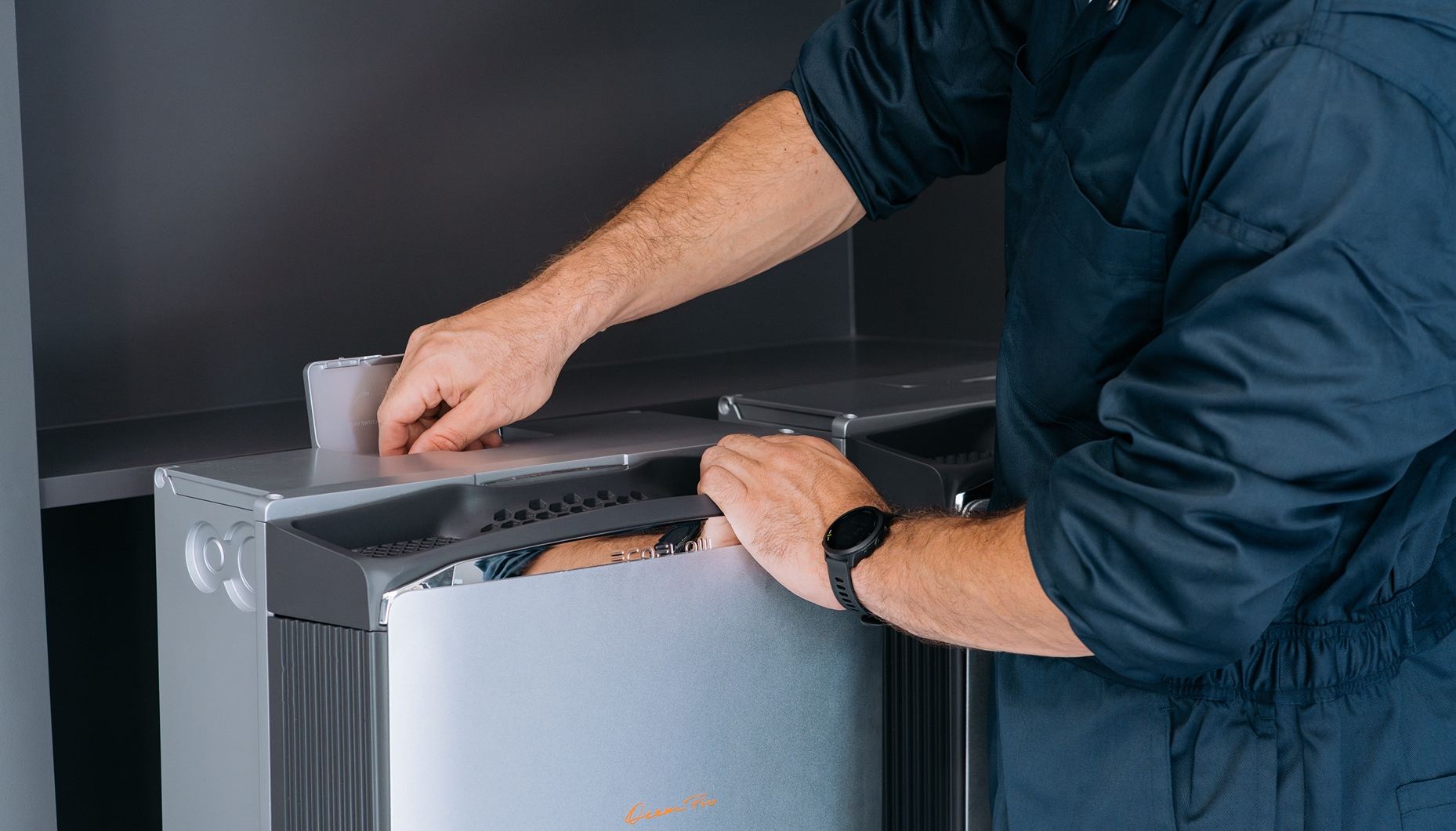 Man in a blue jumpsuit installing a silver EcoFlow home battery storage system.