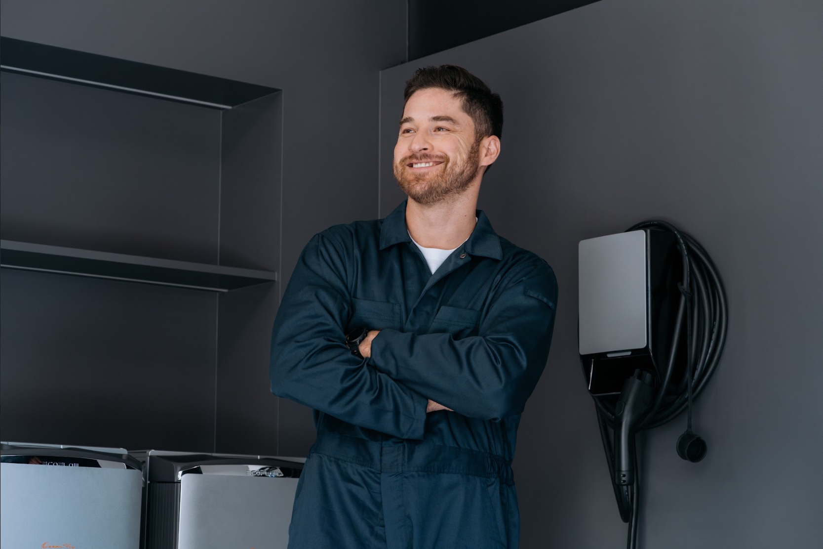 Man in a blue jumpsuit installing a silver EcoFlow home battery storage system.