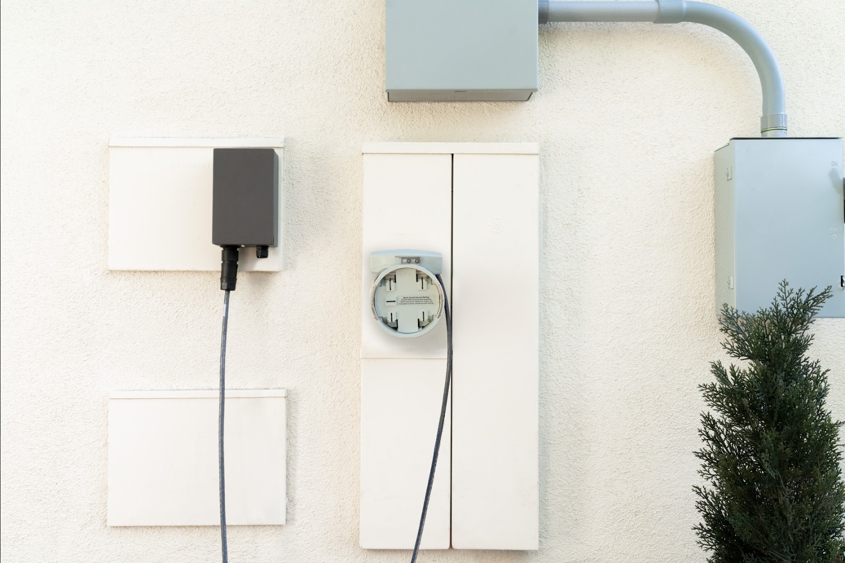 Outdoor electrical installation for the EcoFlow OCEAN Pro system on a light stucco wall, showing grey connection boxes, wiring, and a utility meter base.