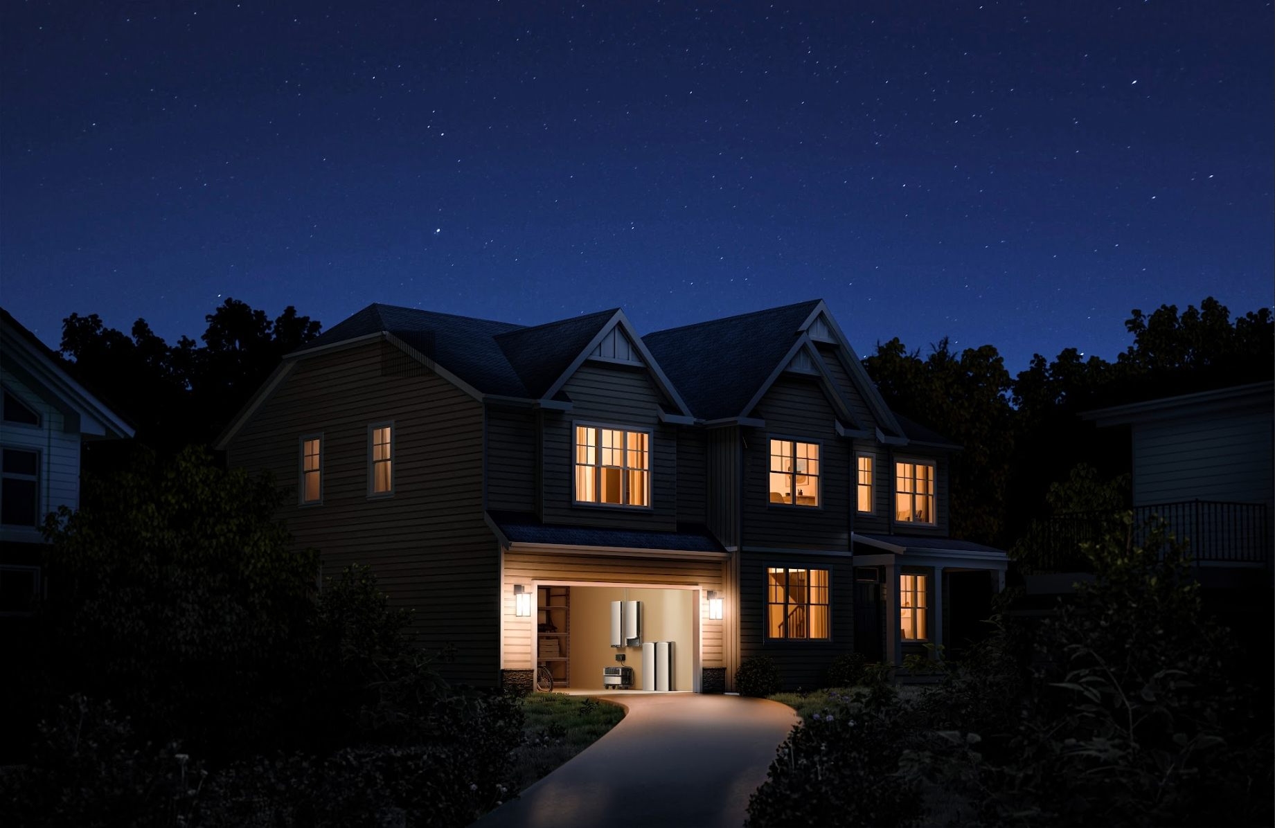 Illuminated house at night with a residential battery backup system visible in the open garage.