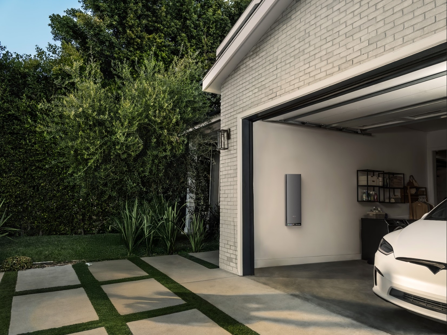 Sleek home energy storage unit mounted on a garage wall next to a parked white electric car.