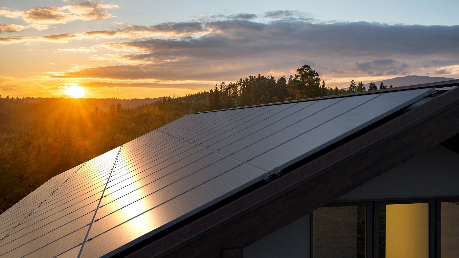 Solar panels installed on a modern roof reflecting a bright golden sunset.