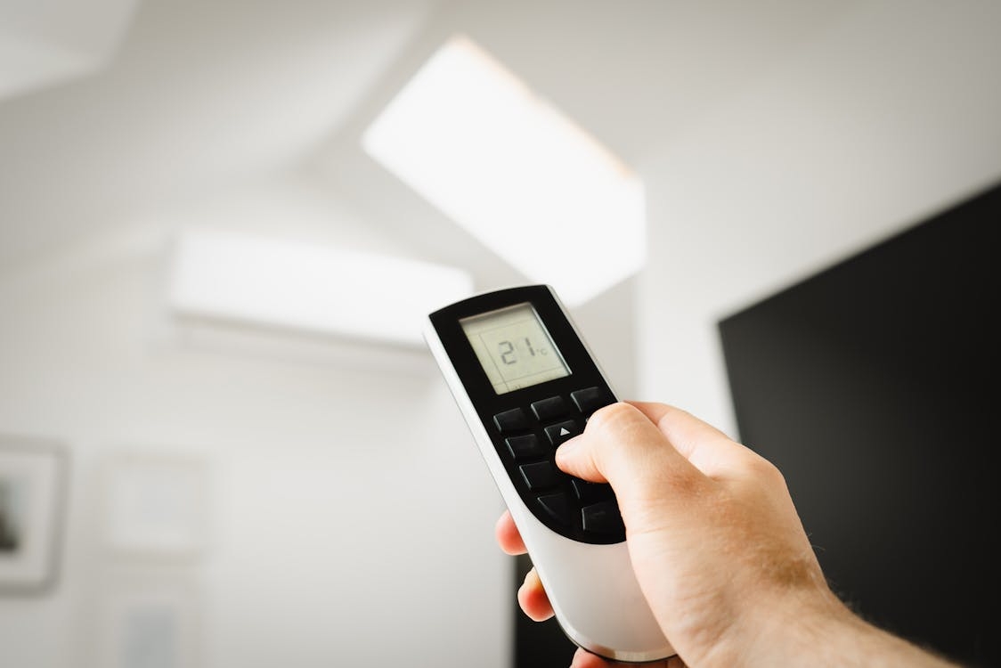 a person is using remote control for an air conditioner