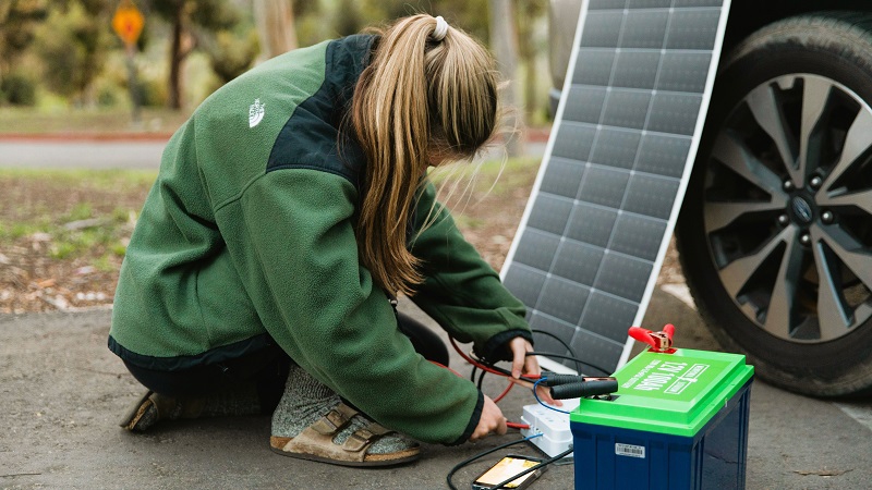 A professional connecting a battery to a solar panel 